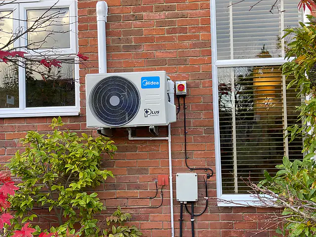 An outdoor air conditioning unit with tidy trunking on a brick house, the kind of air conditioning we fit for homes in Kingston upon Thames